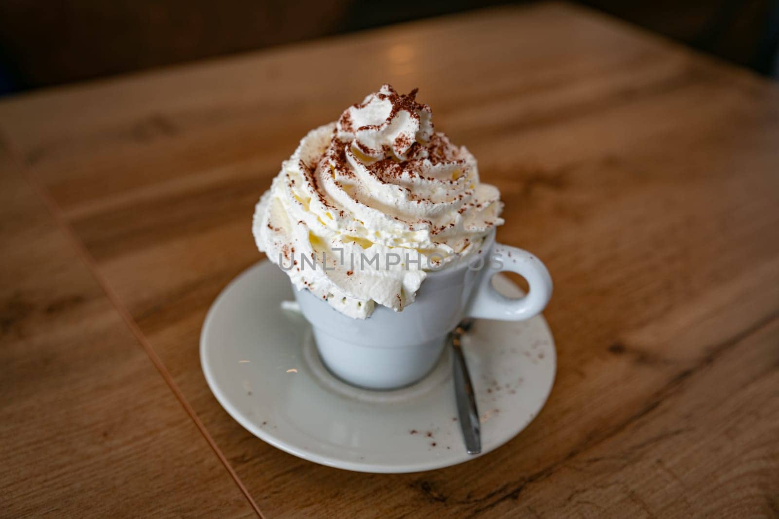 a large cup of cappuccino with lots of whipped cream and chocolate served in a cup in a restaurant