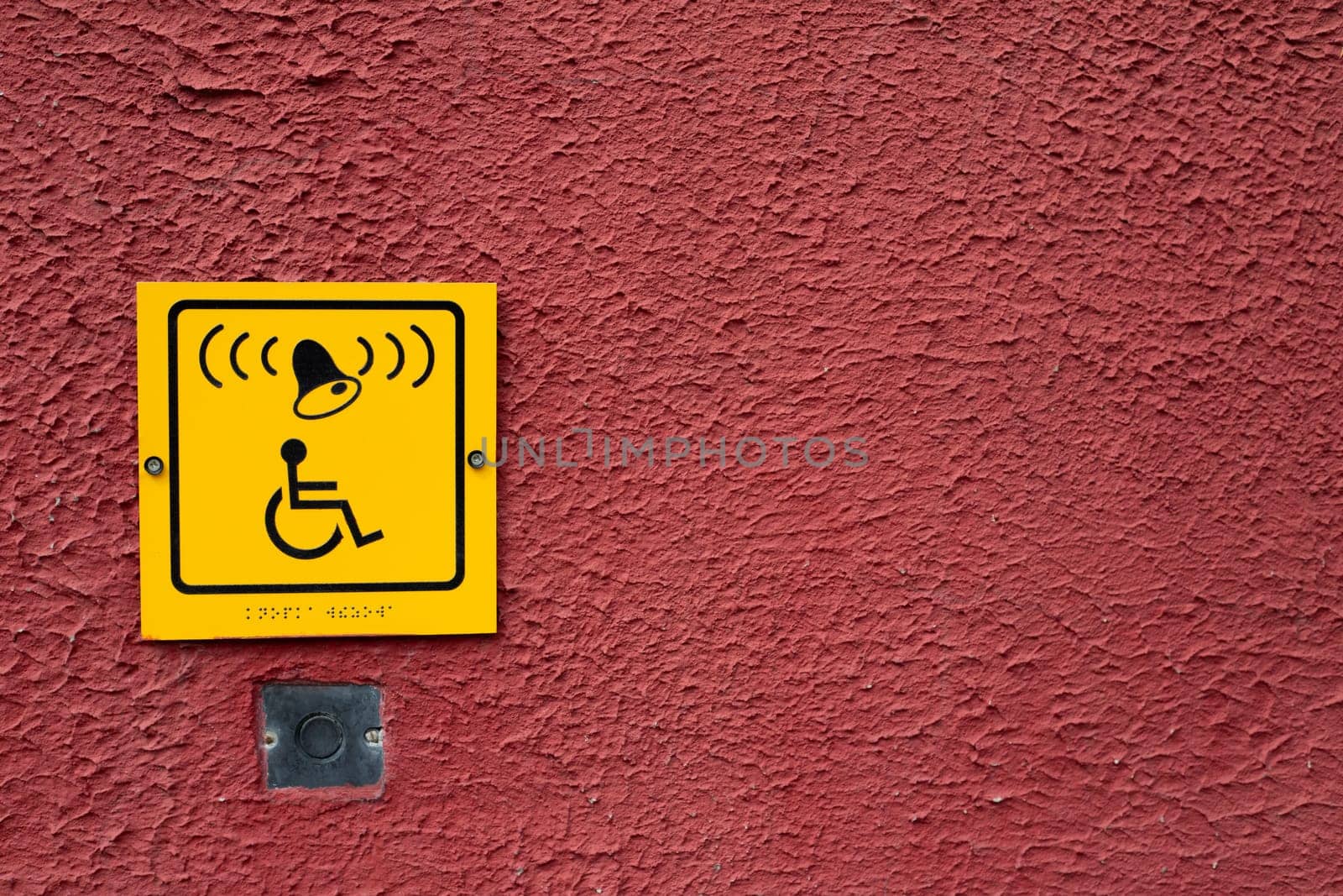 Wheelchair icon with bell and braille text on red wall next to button to call help for disabled person by timurmalazoniia