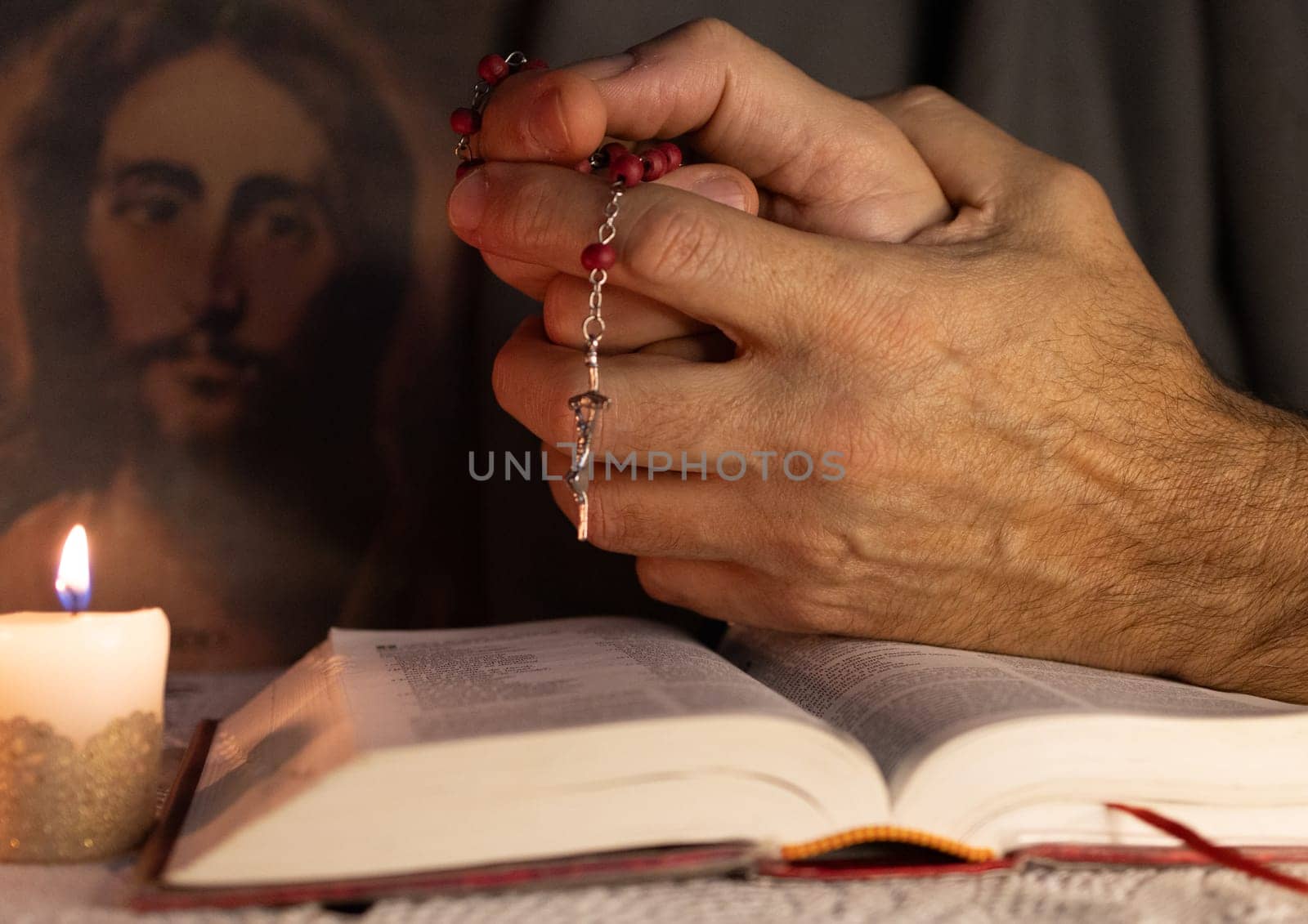 Hands of a man praying to Jesus holding a rosary . by VeroDibe