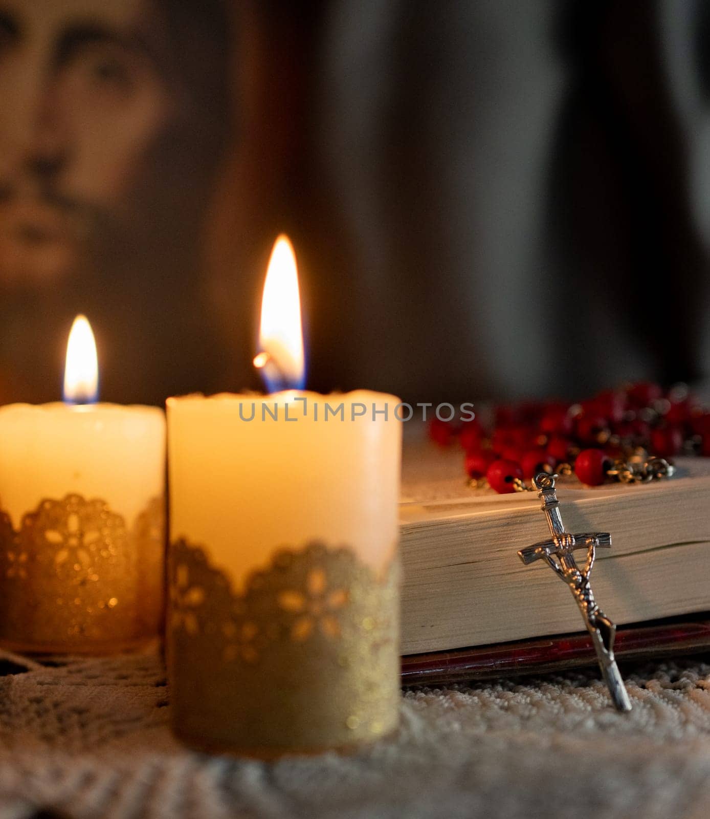 Catholicism culture .Candles lit on an altar. Image of Jesus in the background. by VeroDibe