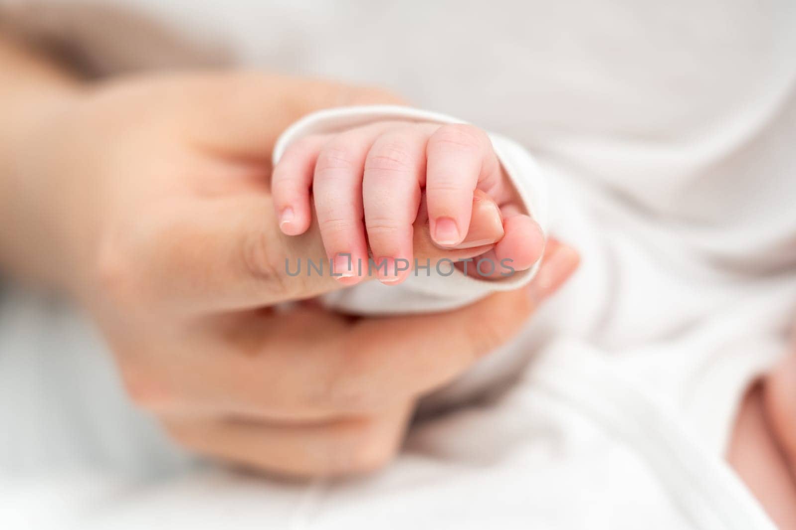 Close-up reveals the intimate connection as sleeping newborn tenderly holds onto mother's finger