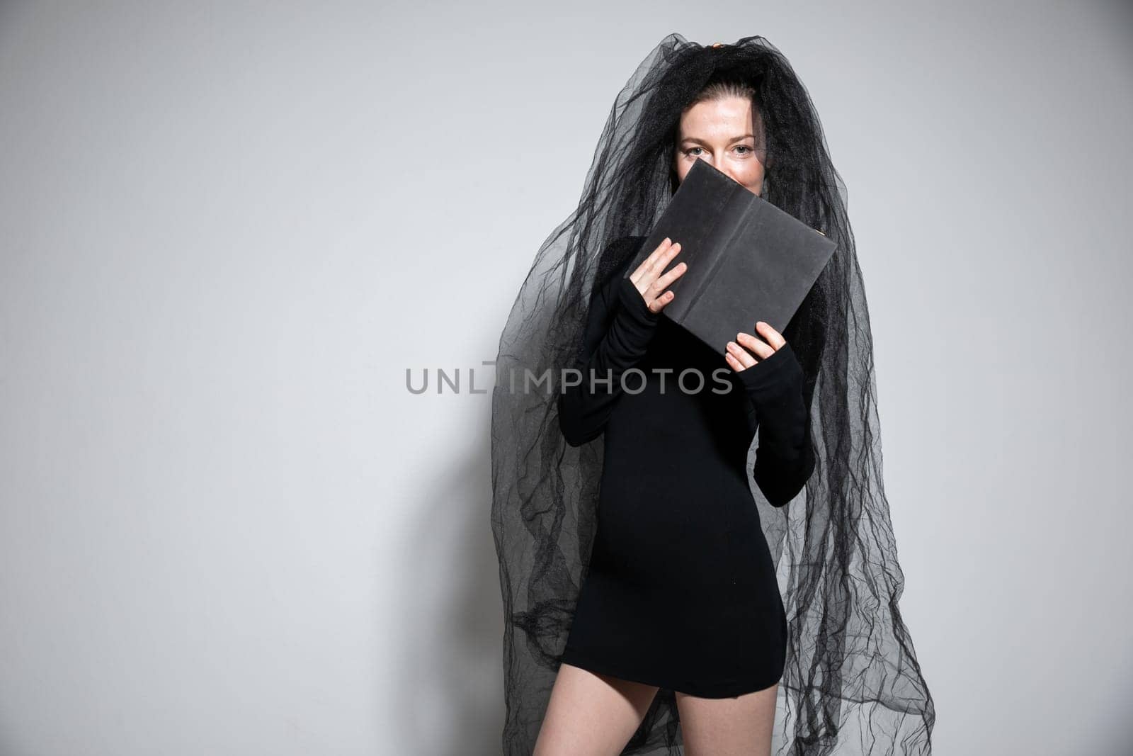 woman in black clothes with veil bride witch witch with book