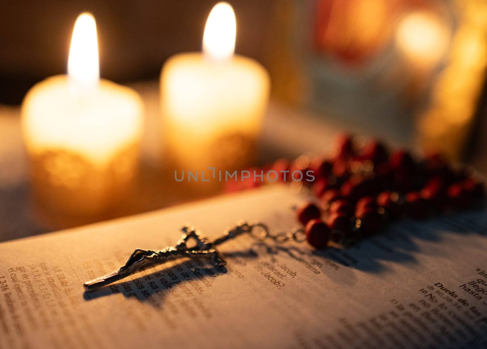 Crucifix on a bible in backlight. Lus of candles on blurred background. by VeroDibe