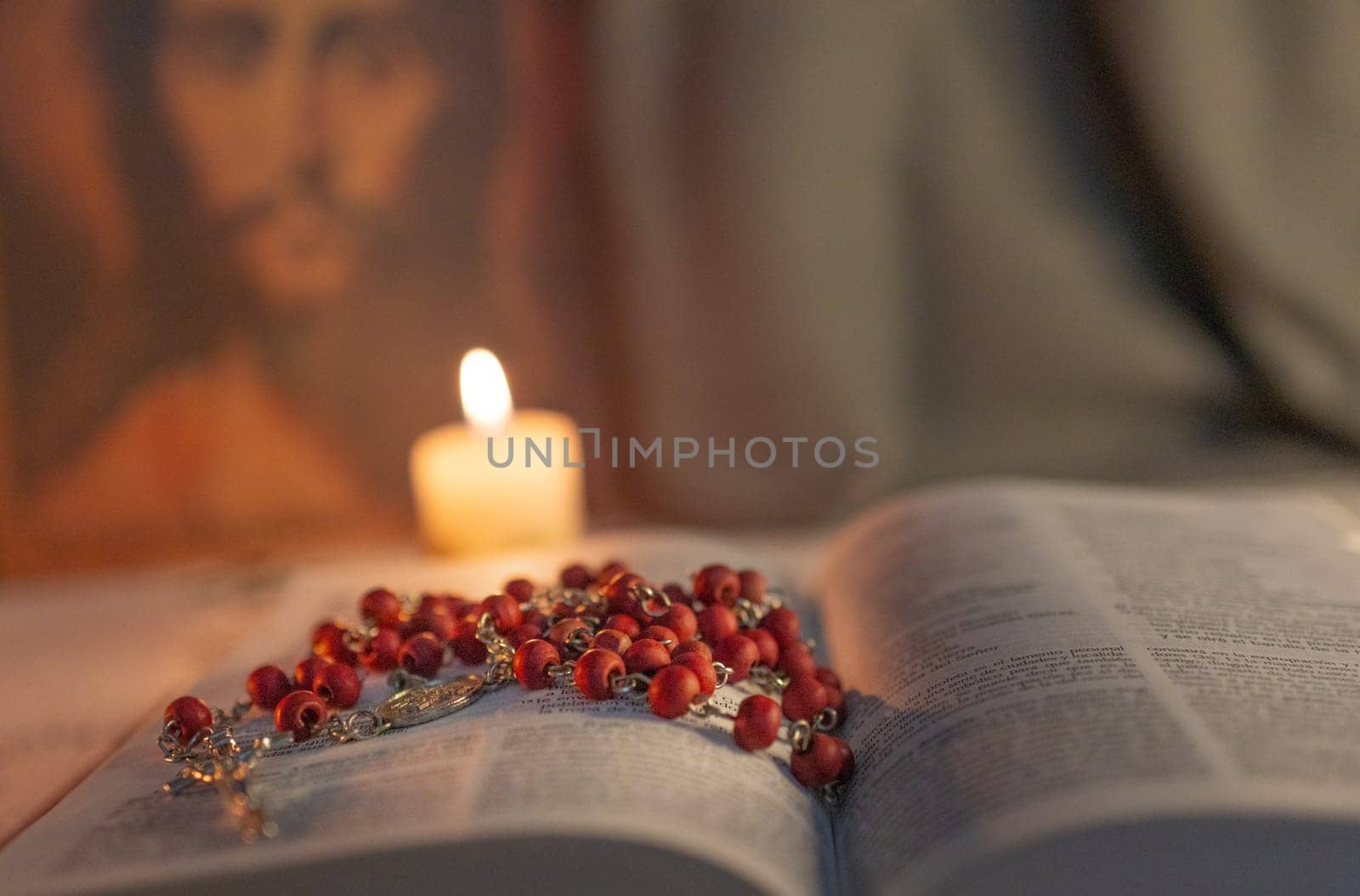 Close up photo of a rosary on The Bible .Jesus face in the blurred background. by VeroDibe