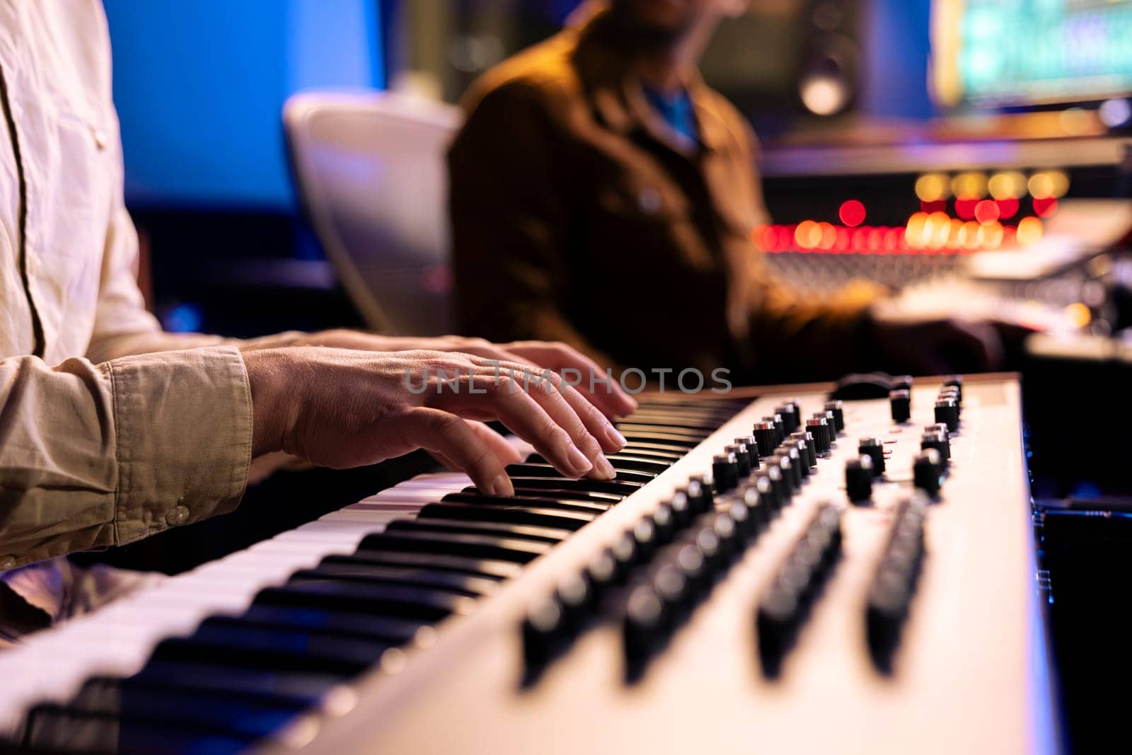 Male singer playing notes on electronic keyboard piano in music recording studio by DCStudio