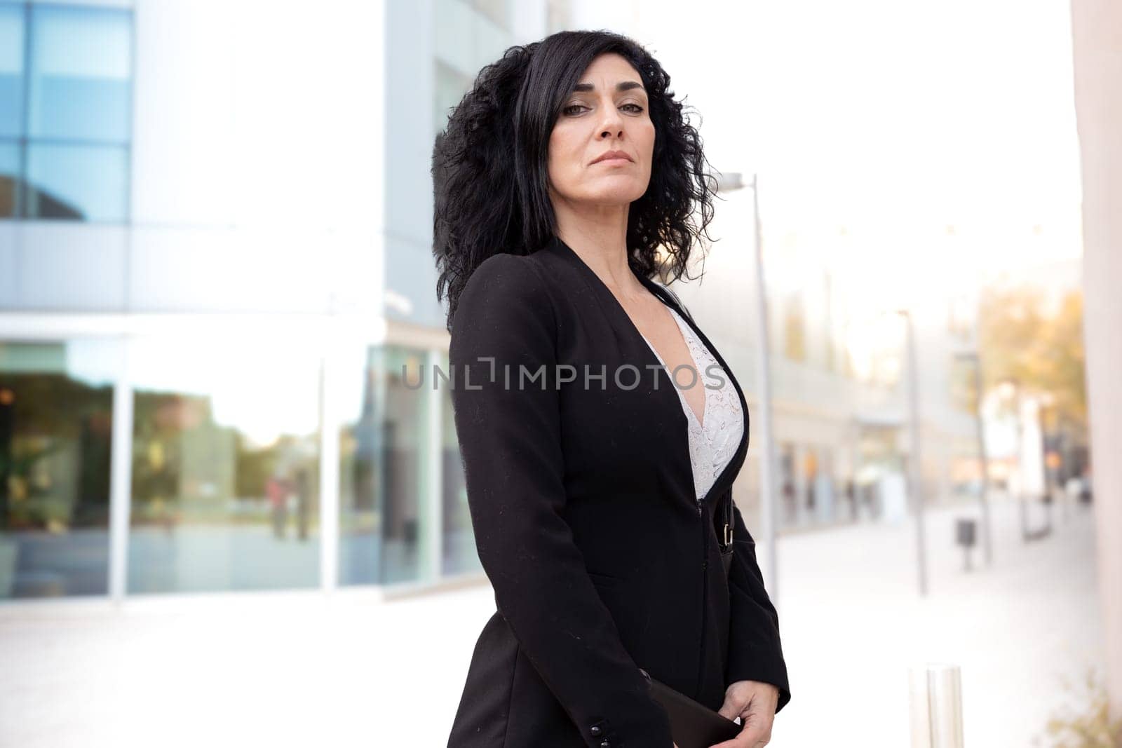 Caucasian business woman looking smiling at camera with standing with arms crossed in an outdoor workspace. Front view of a young lawyer with positive expression looking