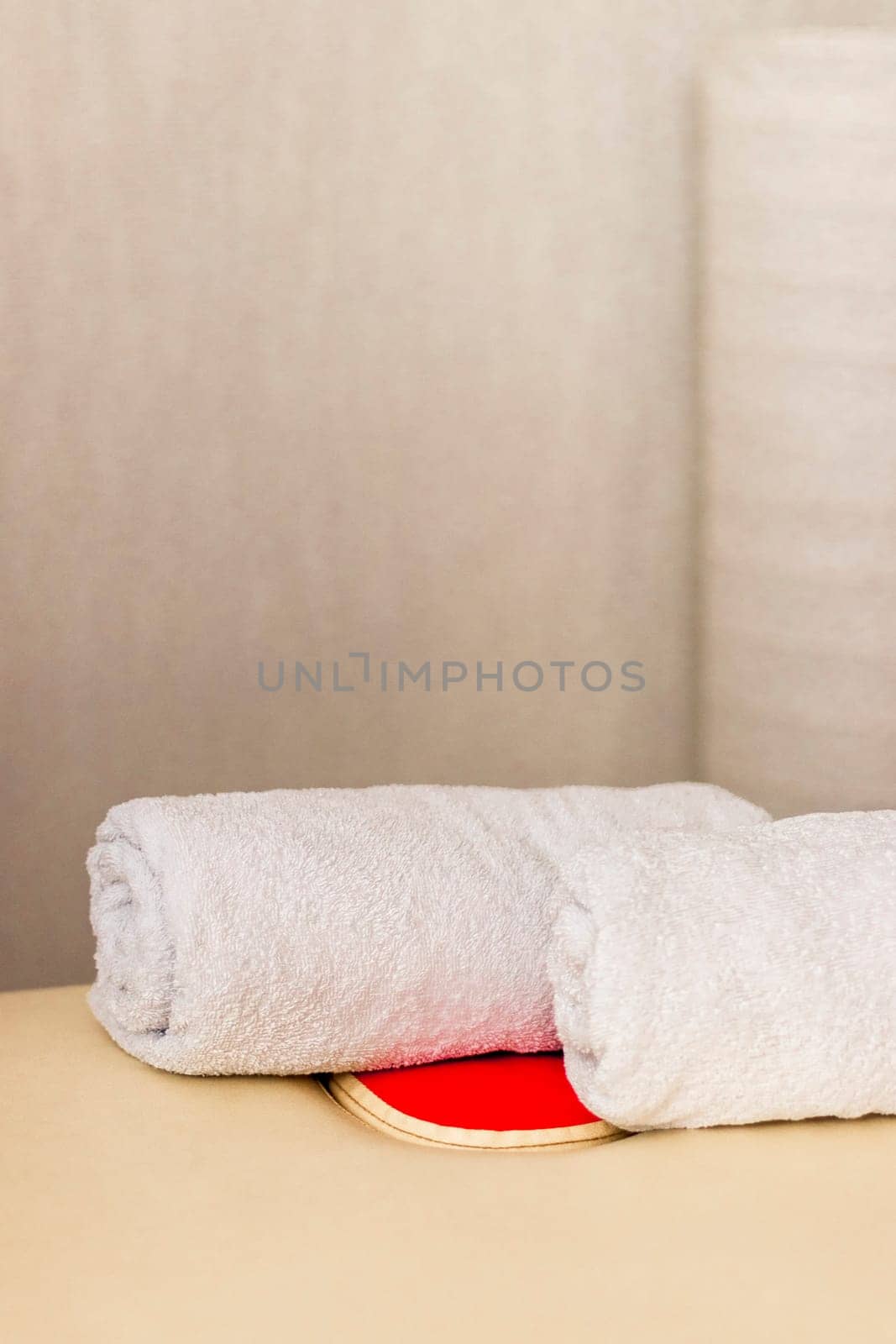 Close up shot of the white towels rolled in the massage couch