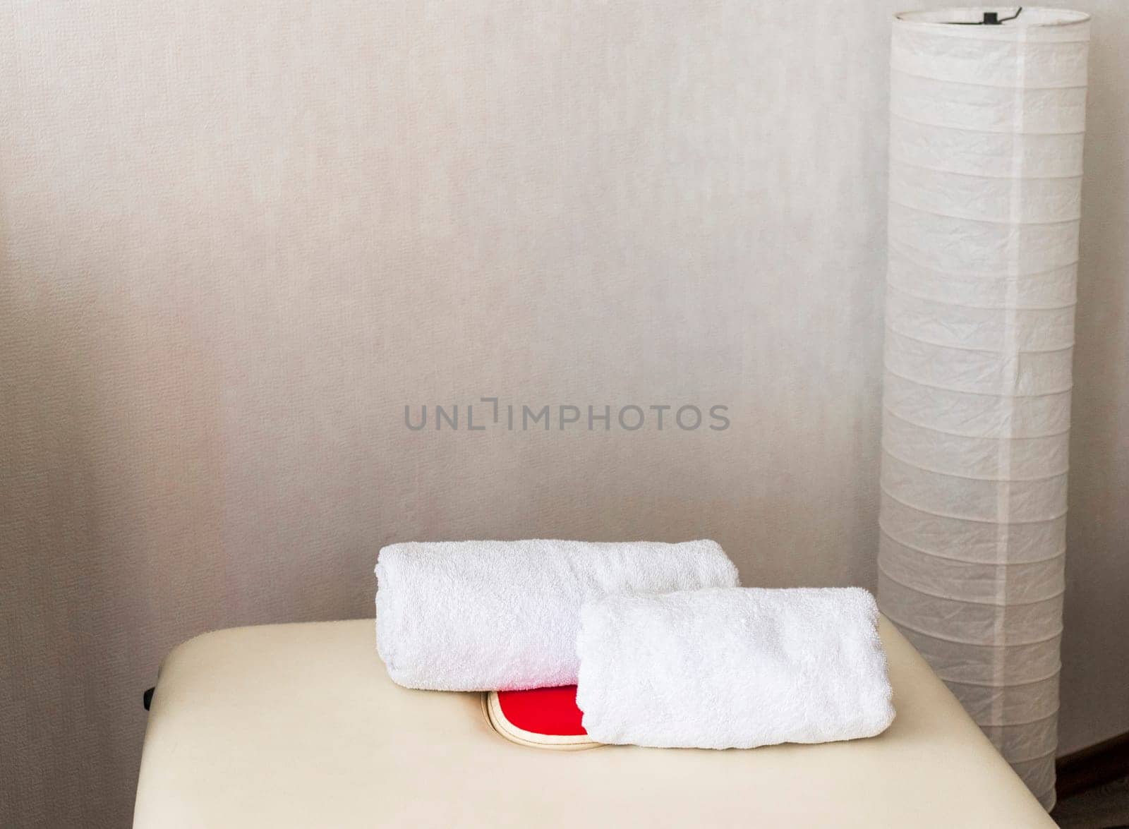 Close up shot of the white towels rolled in the massage couch