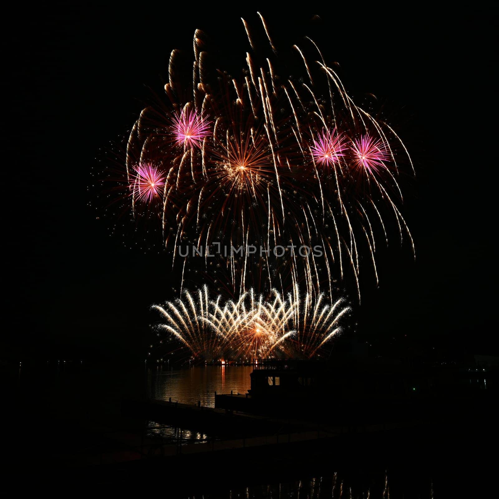 Firework. Beautiful colorful fireworks on the water surface with a clean black background. Fun festival and contest of Firefighters. Brno Dam - Czech Republic.