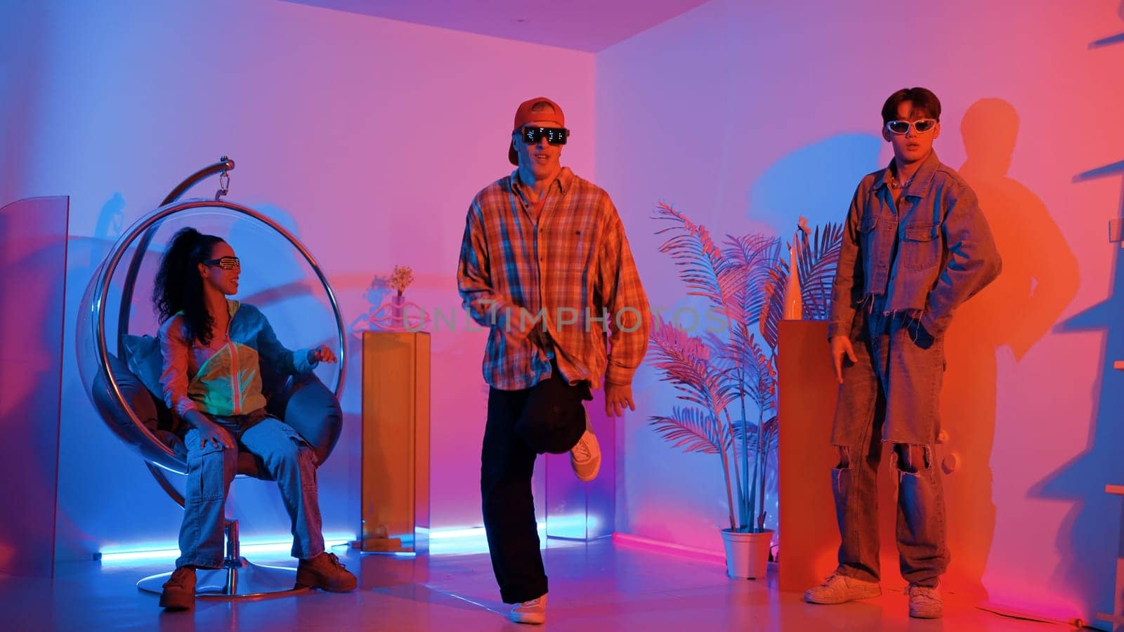 Happy hipster show break dancing while multicultural friend with casual cloth cheering at studio. Professional street dancer perform hip hop beat or lively rhyme with neon or led light. Regalement.