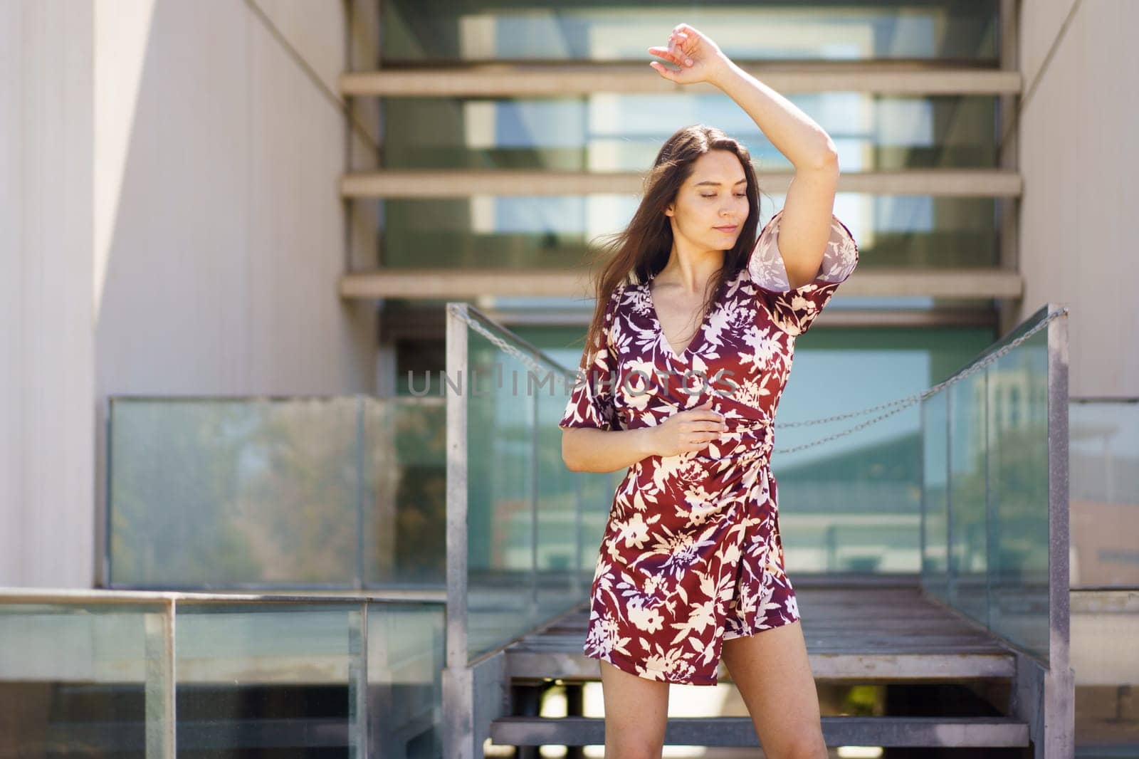 Energetic female dancing a choreography wearing summer dress outdoors in the street