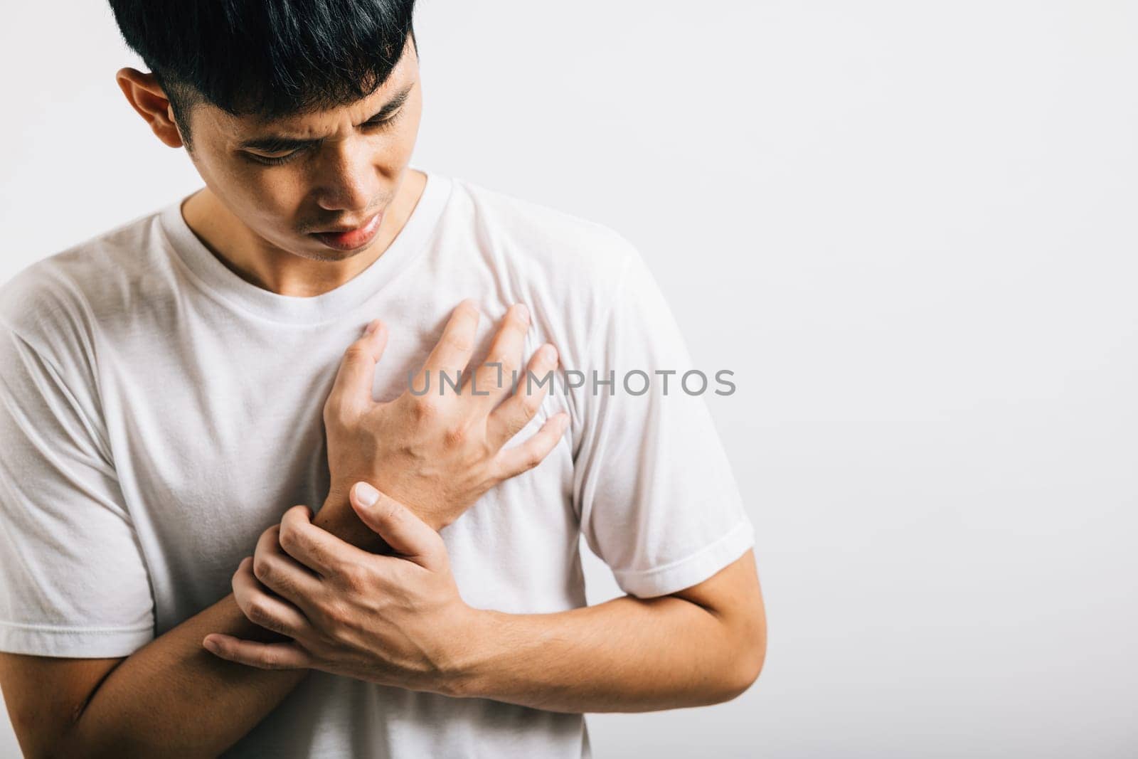 Portrait Asian young man holding his arms around his chest suffering because of a heart attack studio isolated white background, Happy lifestyle men chest pain health discomfort heart problems