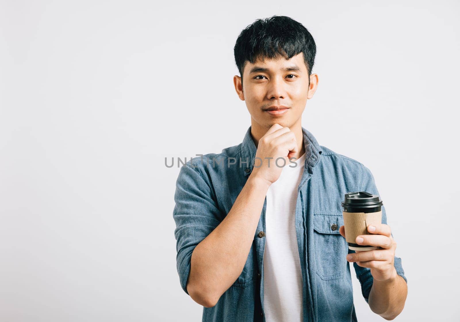 A young Thai man's smiling face while holding a coffee cup. Studio shot isolated on white background with copy space. His happiness is palpable.