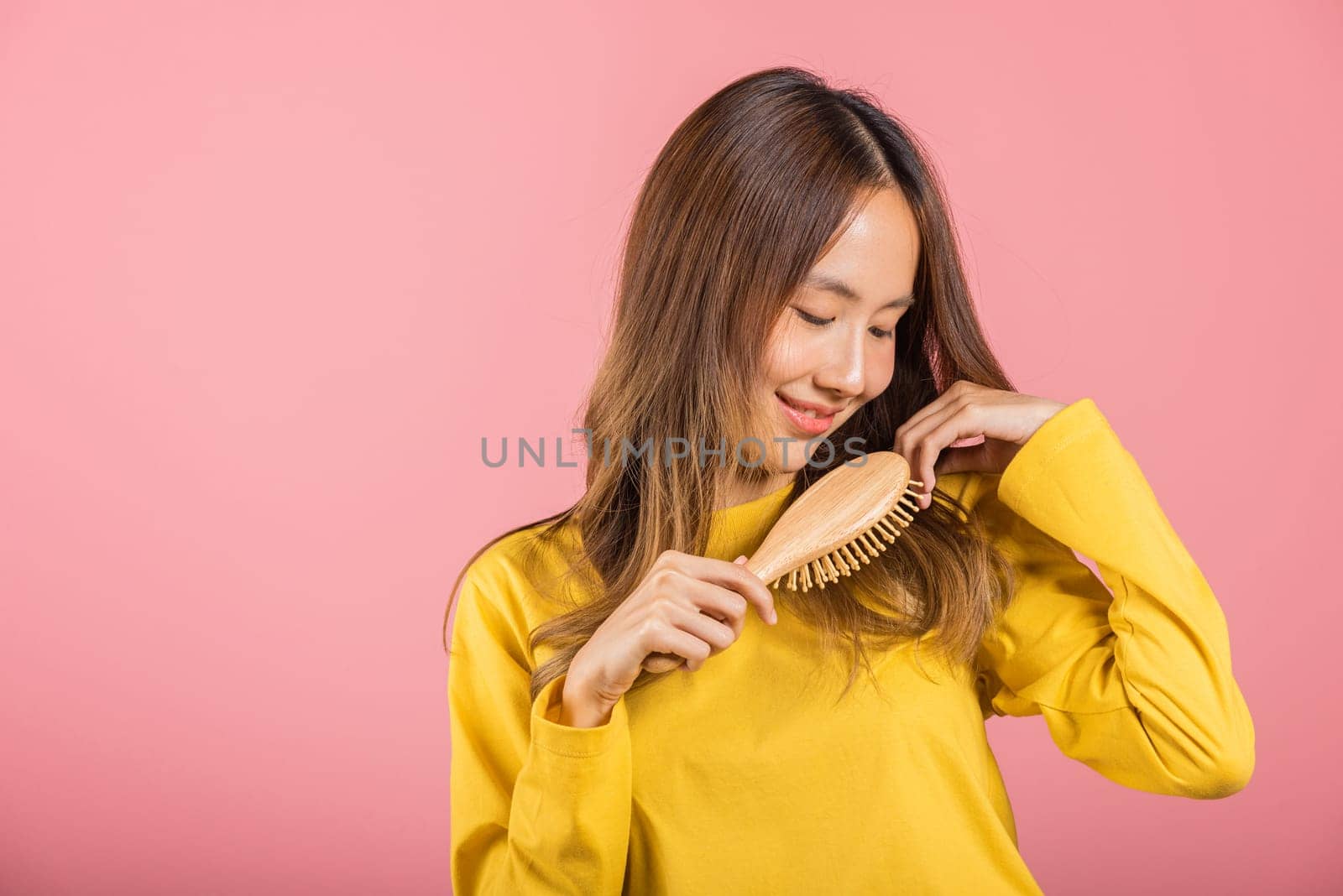Portrait of Asian beautiful young woman smile combing her hair, happy female long healthy hair with hairbrush brushing hair, studio shot isolated by Sorapop