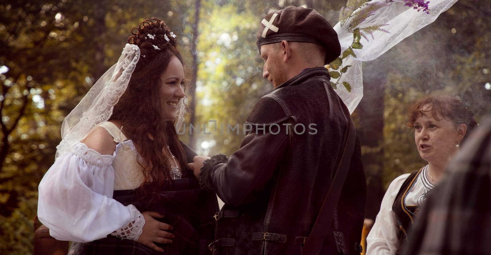 A Scottish groom covers his bride with a Full plaid at the wedding ceremony. Wedding in historical style. Scottish wedding