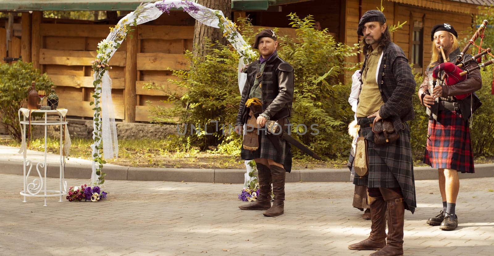 The Scottish groom is waiting for his bride at the altar. Next to him is the lord of the clan and the piper. Scottish wedding.