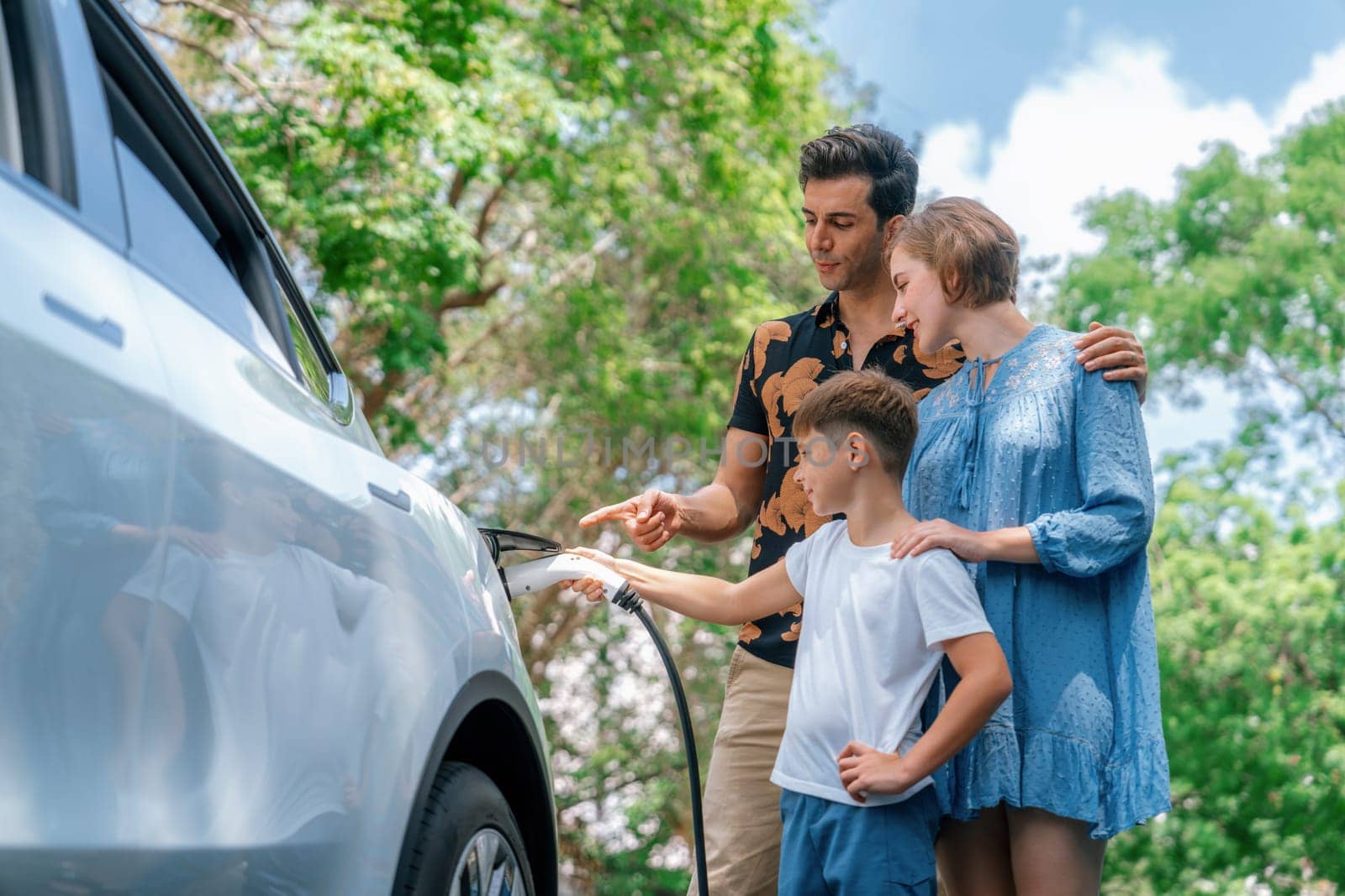 Family road trip vacation with electric vehicle, lovely family recharge EV car with green and clean energy. Natural and eco friendly car travel for sustainable environment. Perpetual