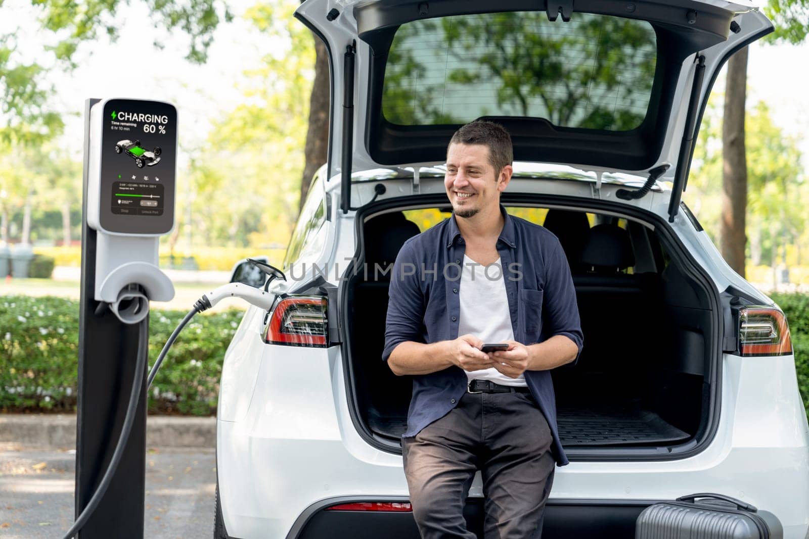 Man using smartphone to pay for electric car charging. Exalt by biancoblue