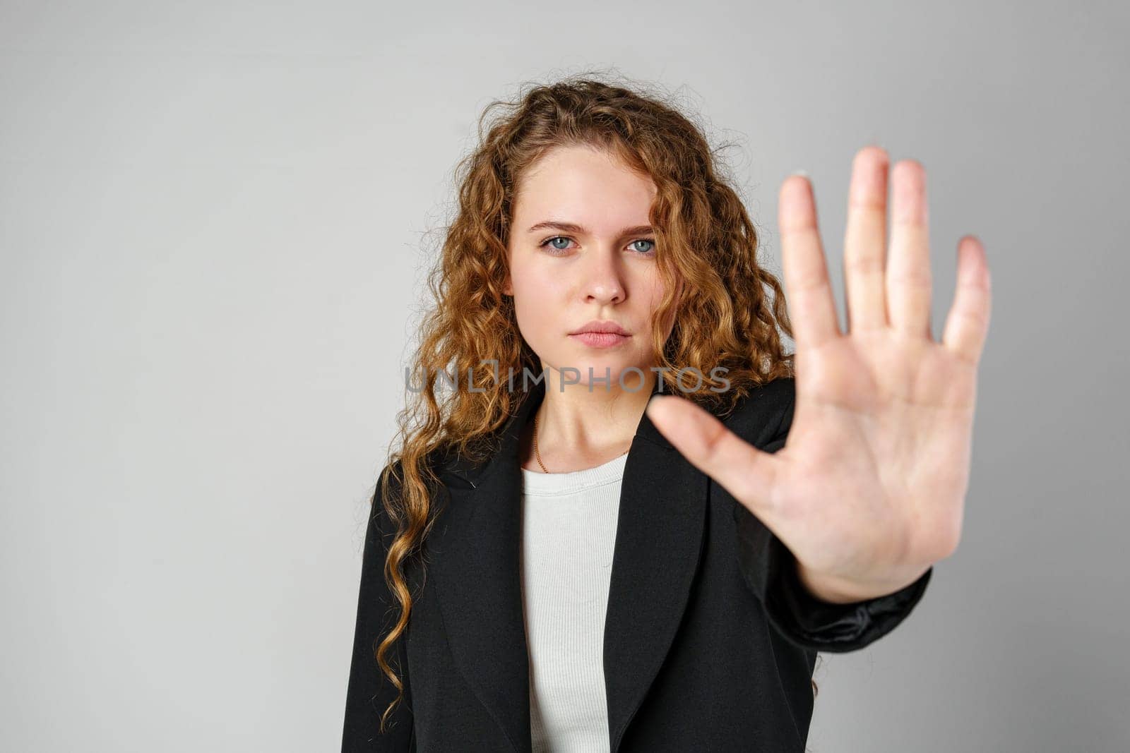 Woman With Curly Hair Holding Hand Up in Studio