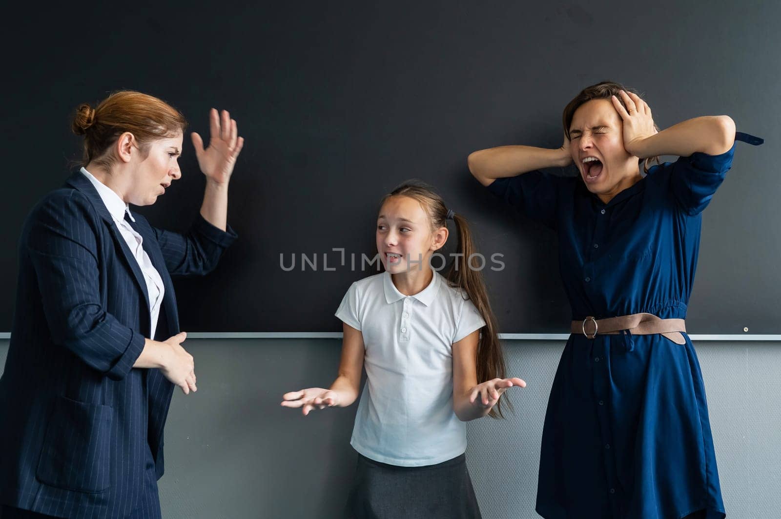 The female teacher screams at the schoolgirl and her mother standing at the blackboard. by mrwed54