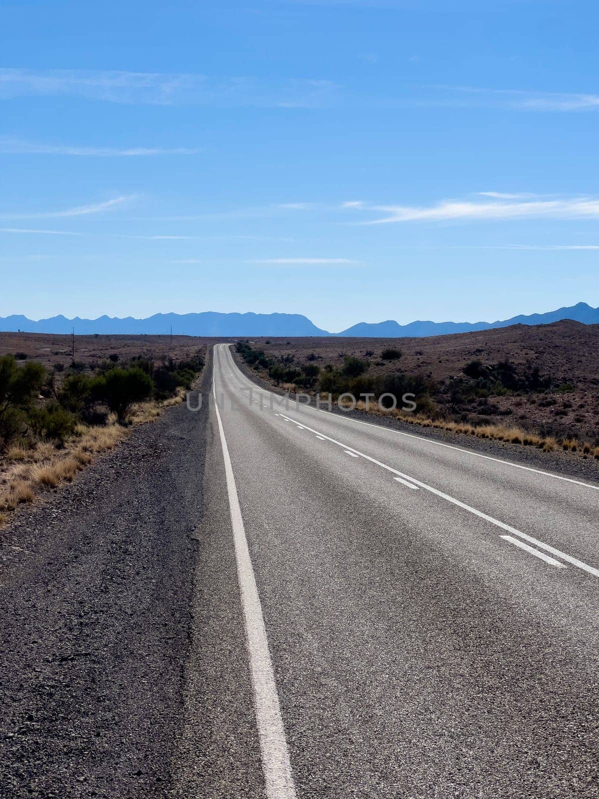 A long, deserted road stretches towards distant mountains in Ikara Flinders Ranges