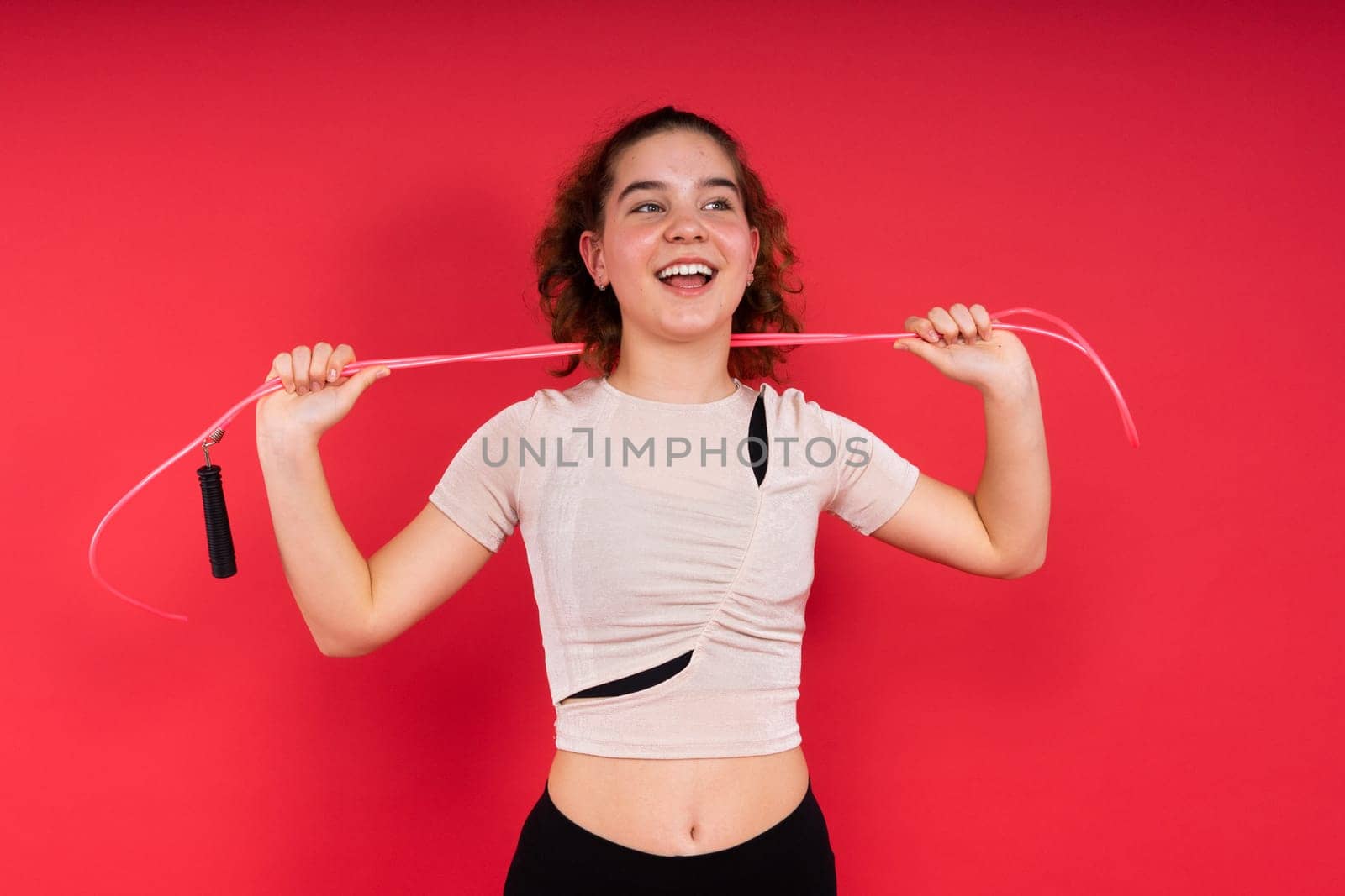 Cute teenage girl with a jumping rope looking at camera and smiling while having workout