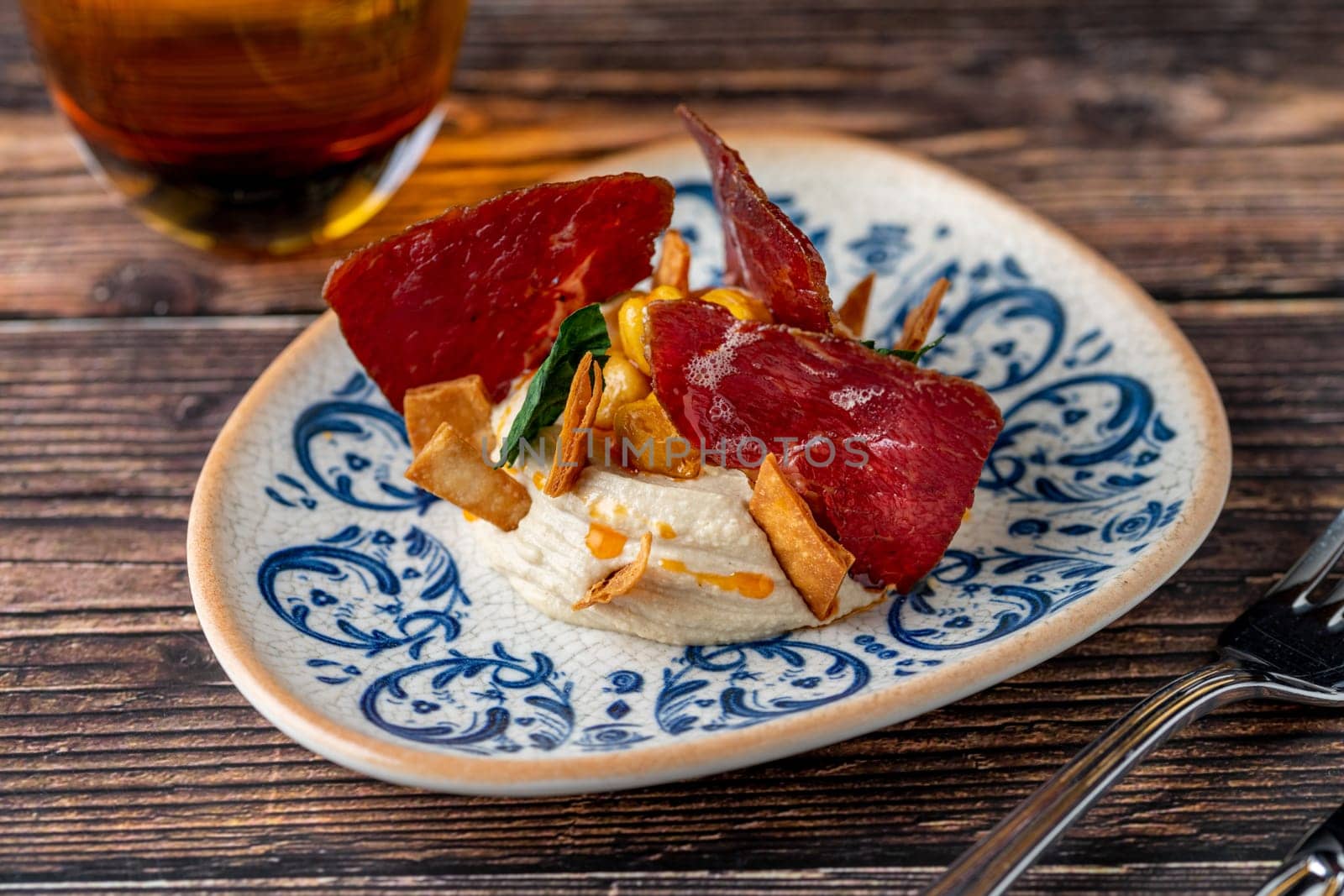 Hummus with pastrami, traditional Turkish dish, on wooden table by Sonat