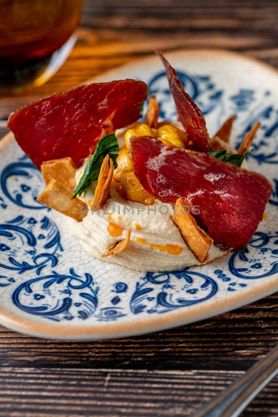 Hummus with pastrami, traditional Turkish dish, on wooden table by Sonat