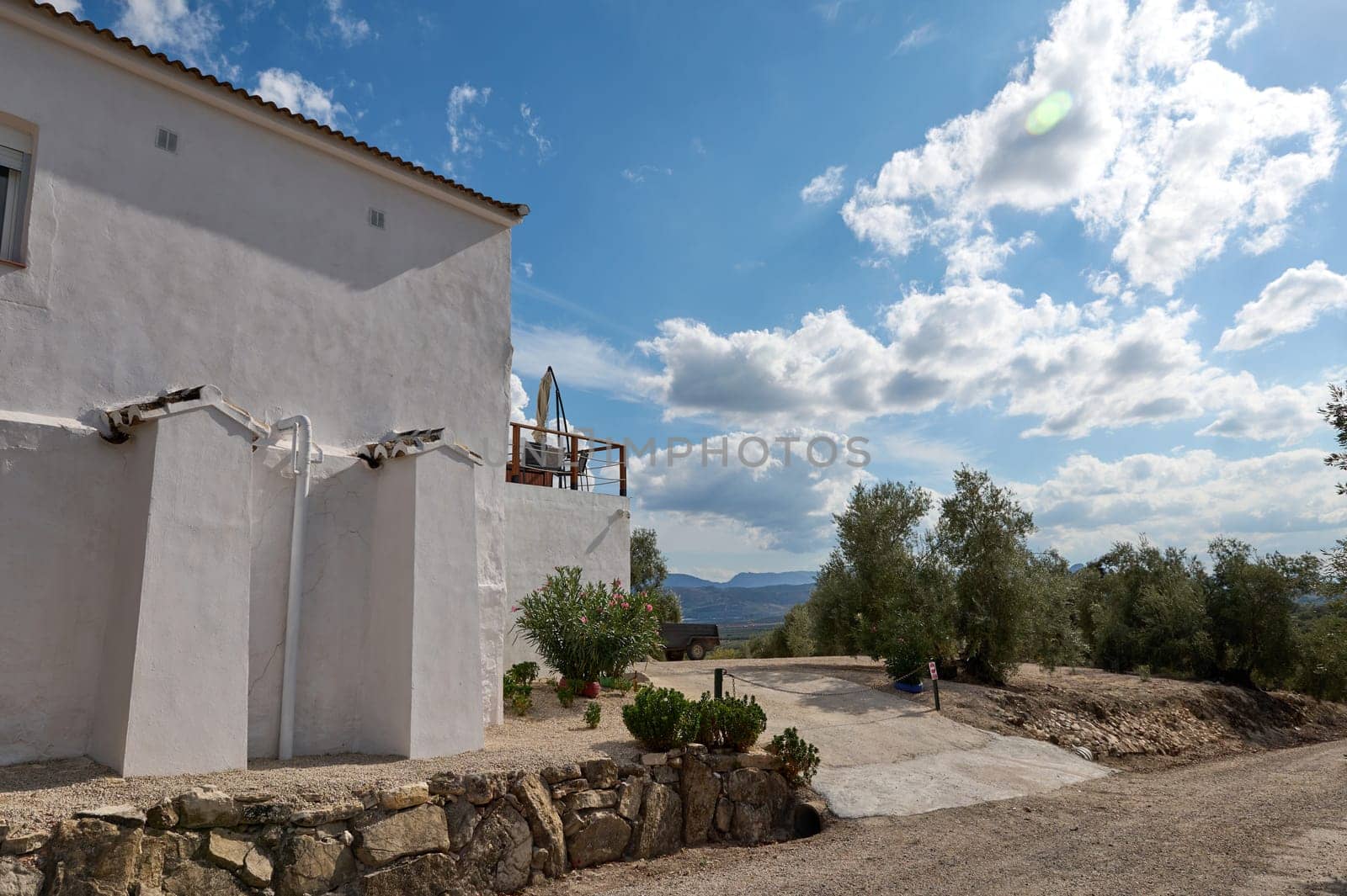 Rural farmhouse with whitewashed walls surrounded by greenery and scenic views under a clear blue sky. Peaceful countryside setting perfect for relaxation and escape from urban life.