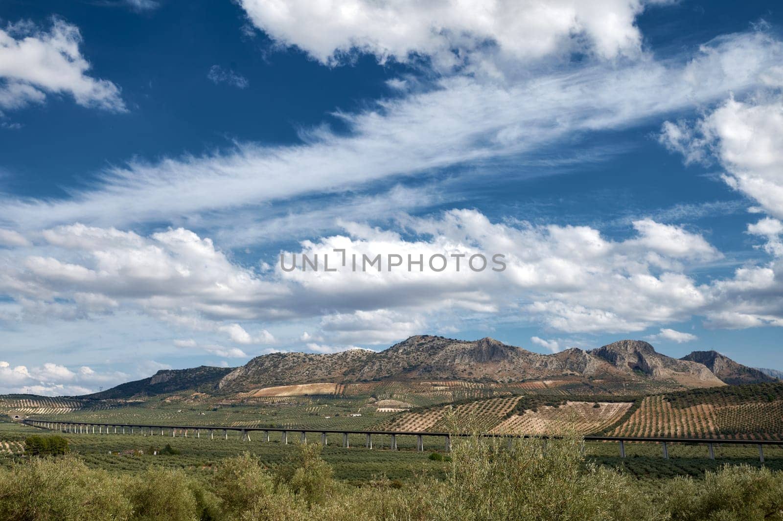 Scenic view of mountains with railway bridge under blue sky by artgf