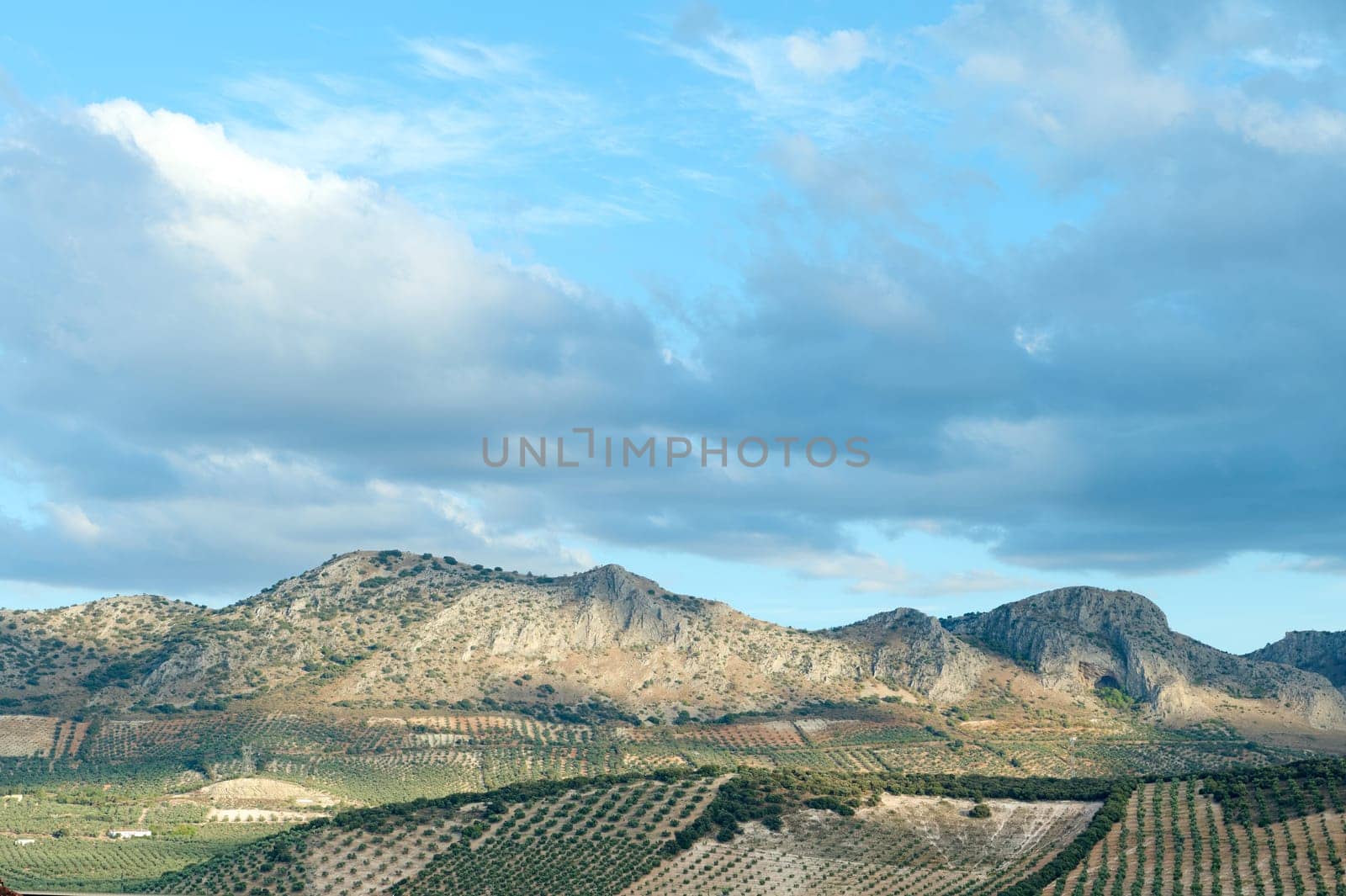 Beautiful landscape featuring mountains, expansive agricultural fields, and a partly cloudy sky. The scene showcases the serenity and natural beauty of rural countryside.