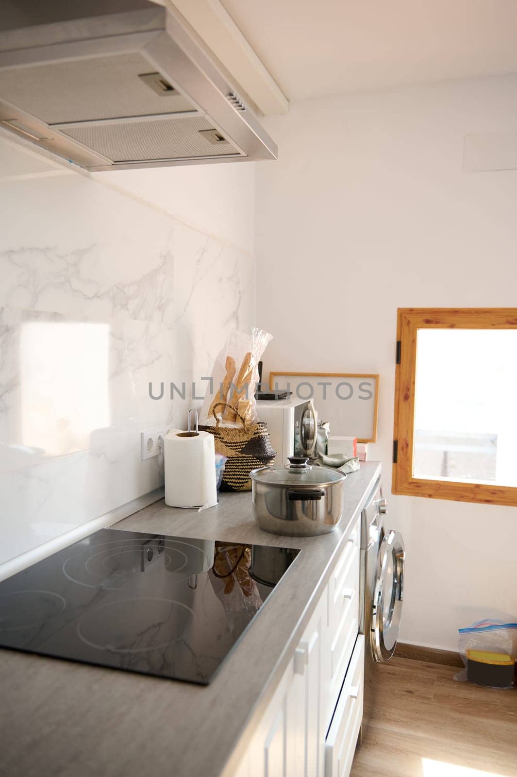 Bright and modern kitchen featuring stainless steel appliances, an electric stovetop, and natural light from a wooden-framed window. Perfect for home cooking and interior design inspiration.