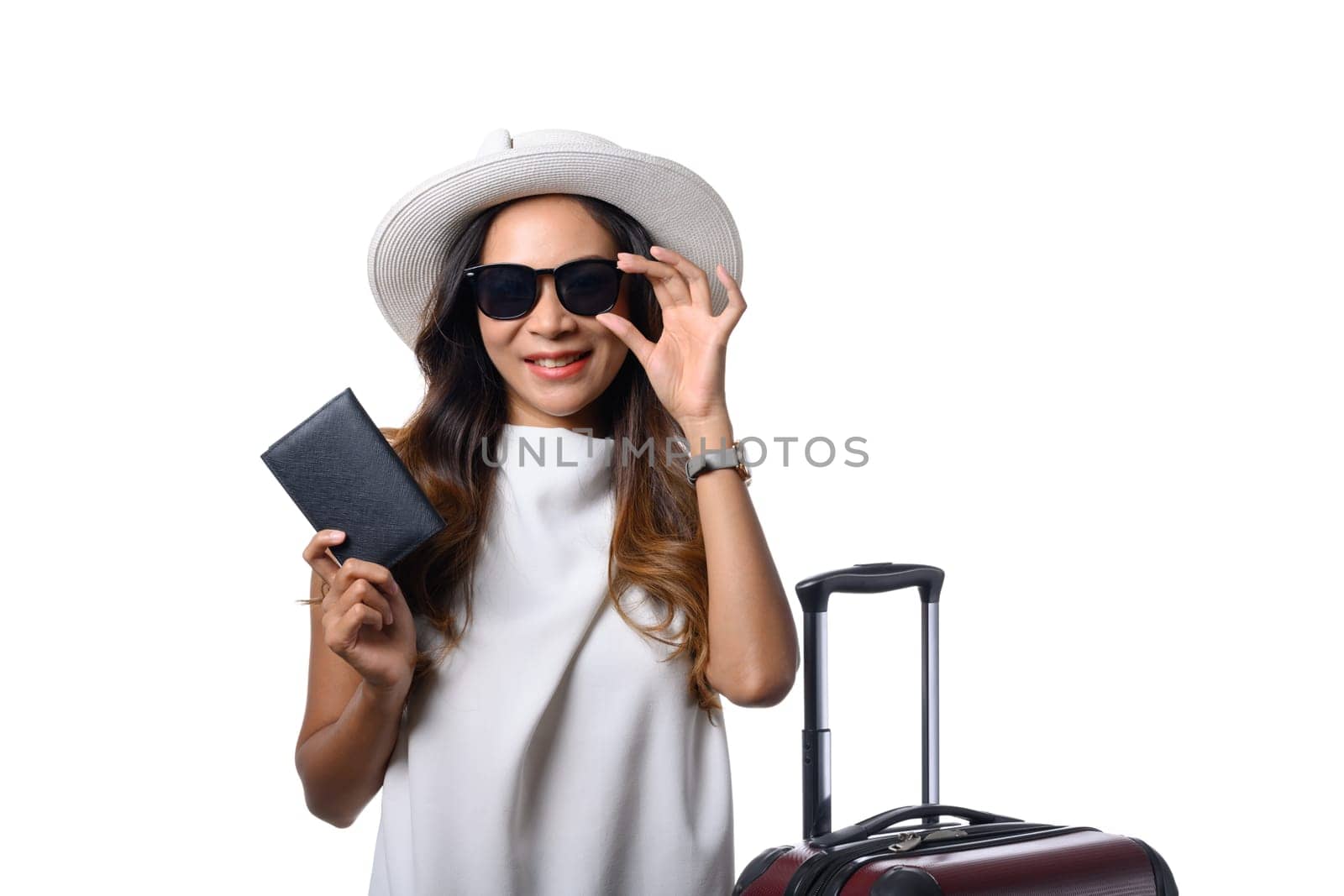 Smiling woman traveler holding passport standing with suitcase on white background. Vacation and travel concept.