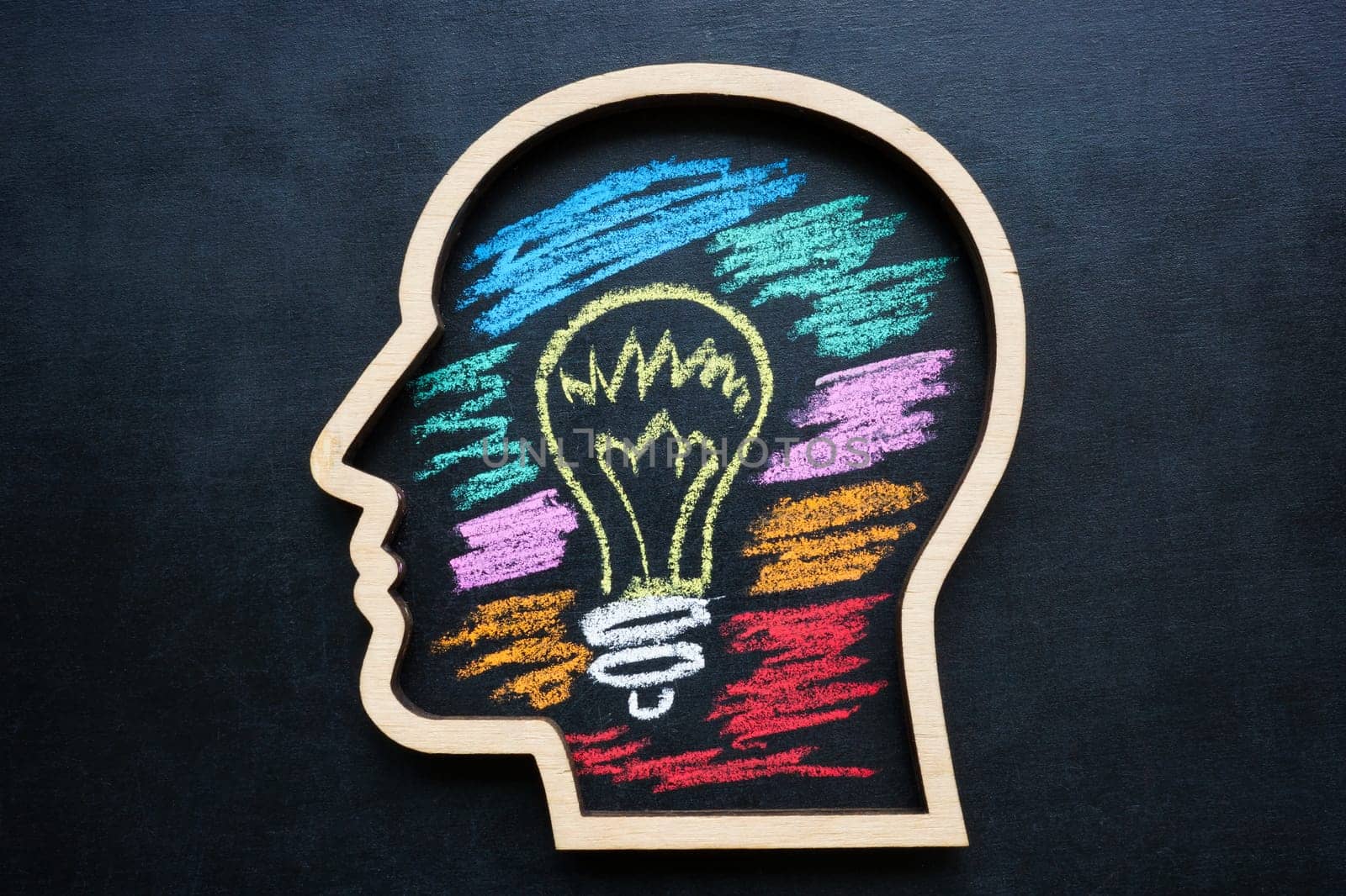 Outline of a head with light bulb drawn in chalk. Creative thinking skills and development.