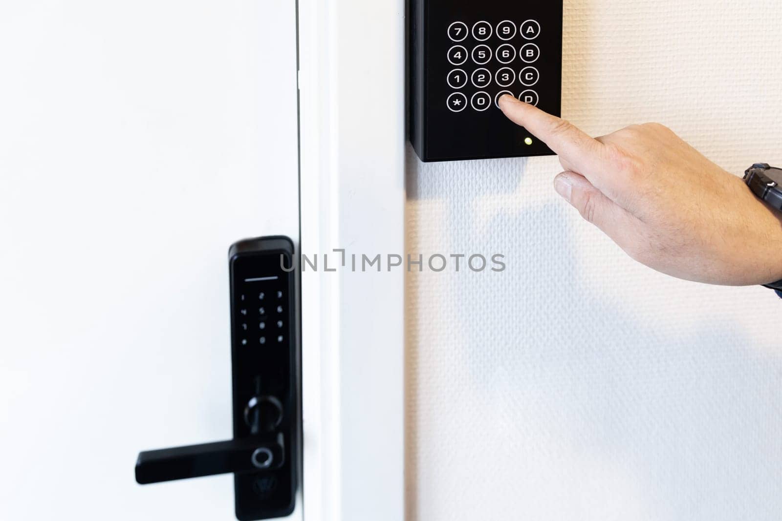 A human hand presses buttons with numbers to enter a code for the front door.