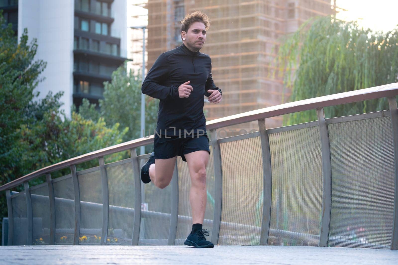 Young caucasian athlete with headphones training outdoors.