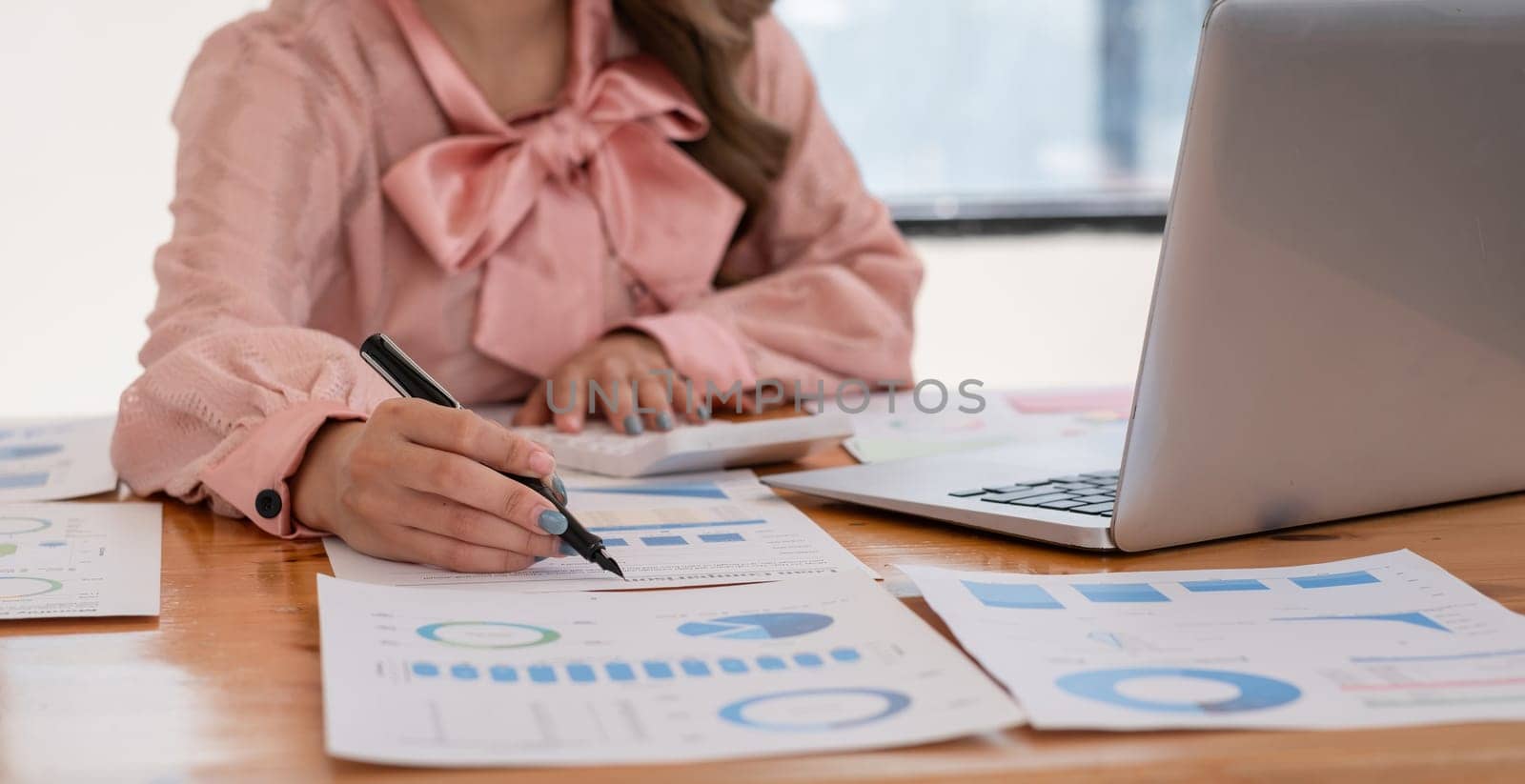 A young accountant working diligently on financial documents at a desk, using a laptop in a modern office environment.