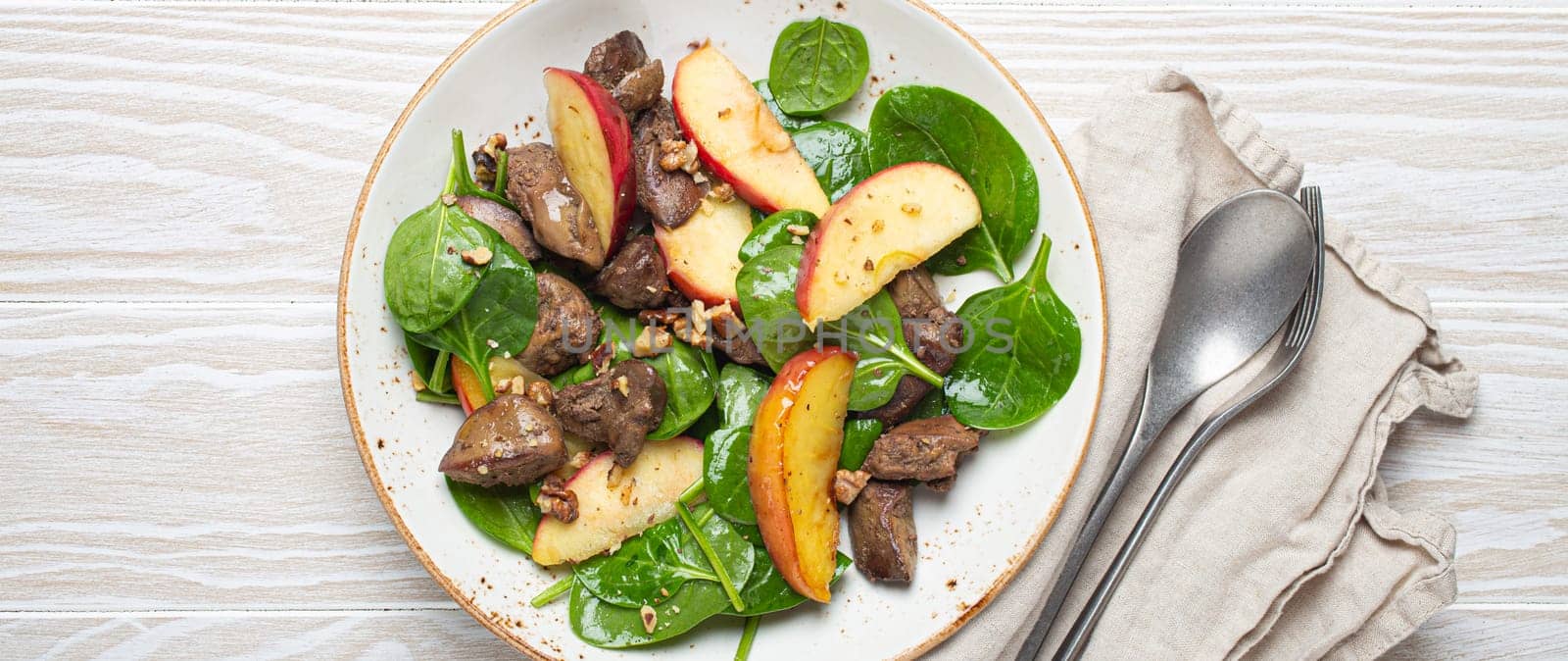 Healthy Salad with Iron Rich Ingredients Chicken Liver, Apples, Fresh Spinach and Walnuts on White Ceramic Plate, White Wooden Background From Above.