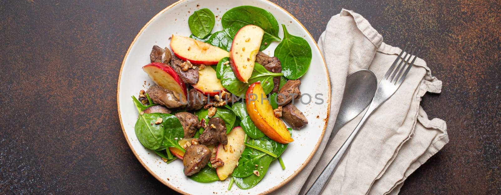 Healthy Salad with Iron Rich Ingredients Chicken Liver, Apples, Fresh Spinach and Walnuts on White Ceramic Plate, Dark Brown Rustic Stone Background From Above. by its_al_dente