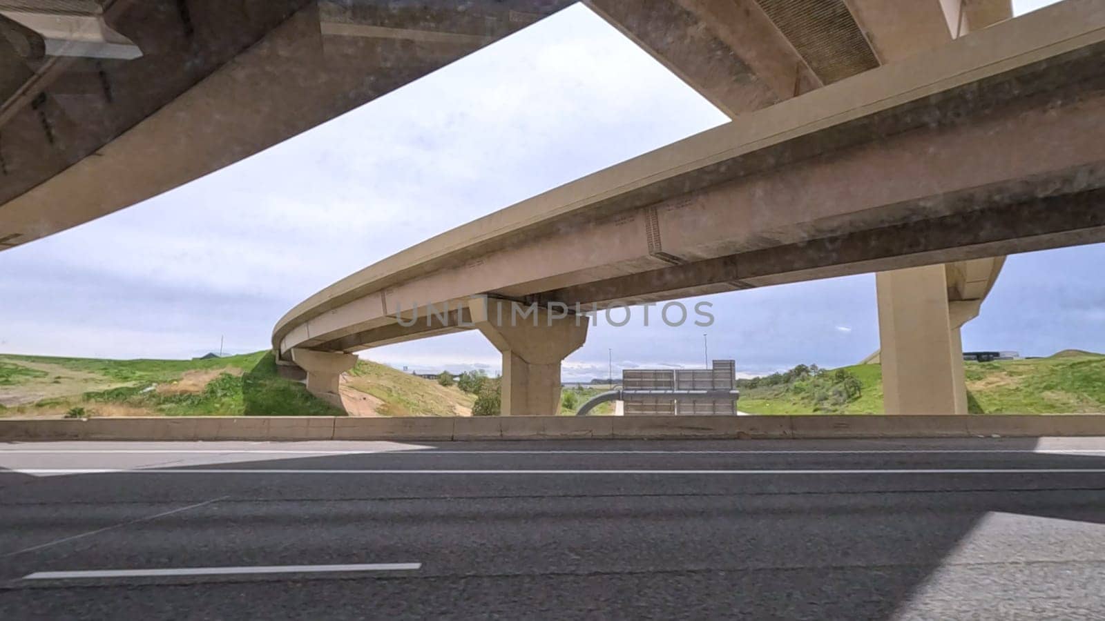 A dynamic view of the elevated highway overpass in South Denver, showcasing the intricate concrete structures and modern road design. The image captures the expansive lanes and surrounding landscape under a cloudy sky.