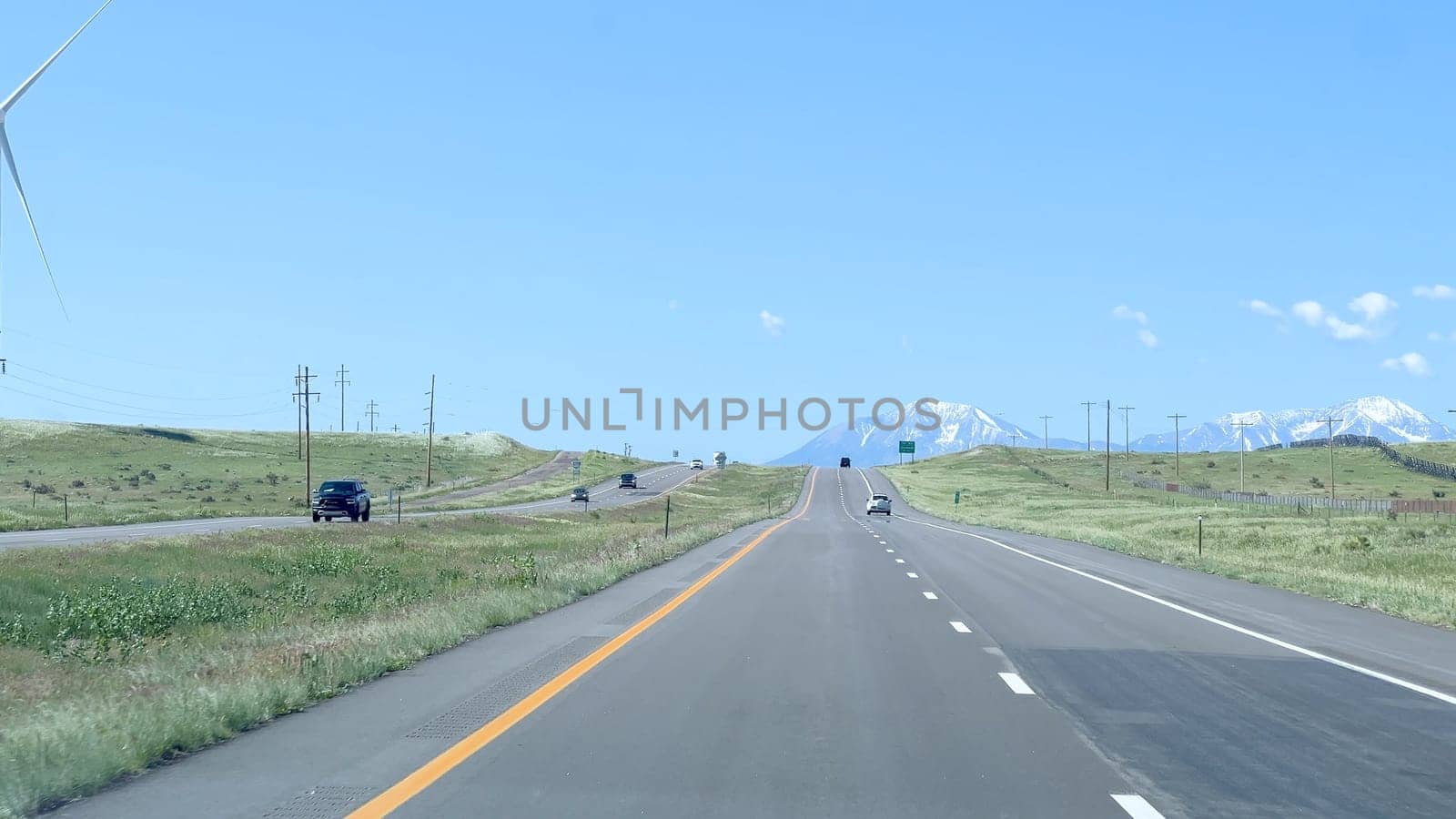 Wind Turbines Alongside a Highway with Mountain Views in Colorado by arinahabich