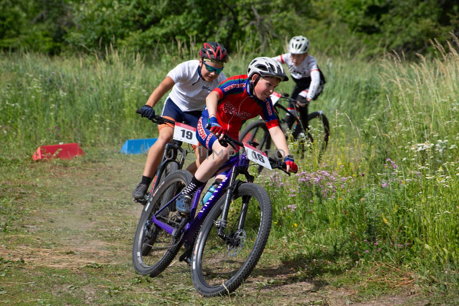 Kursk, Russia, June 15, 2024: Children cyclist in equipment fighting for position in turn at cross-country cycling competition