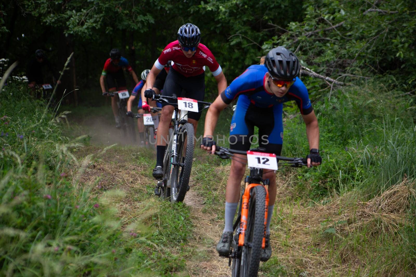 Kursk, Russia, June 15, 2024: Young cyclists overcome obstacles over hills on mountain bikes, cross country cycling competition