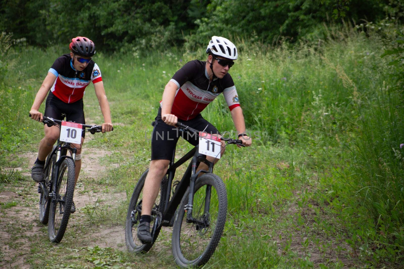 Kursk, Russia, June 15, 2024: Young guys on bicycles in turn at mountain bike competition fighting for position, cross-country cycling