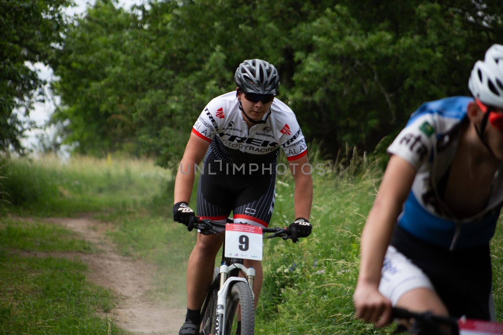 Young cyclist at mountain bike competition in forest by timurmalazoniia