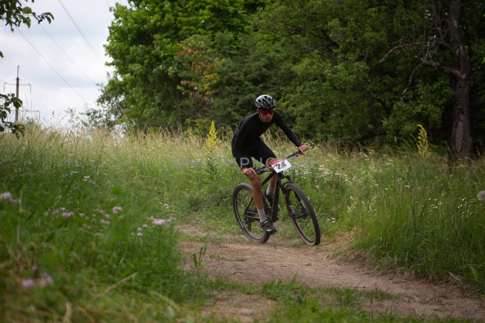 Kursk, Russia, June 15, 2024: Bike racer takes a turn on trail in forest at mountain bike competition