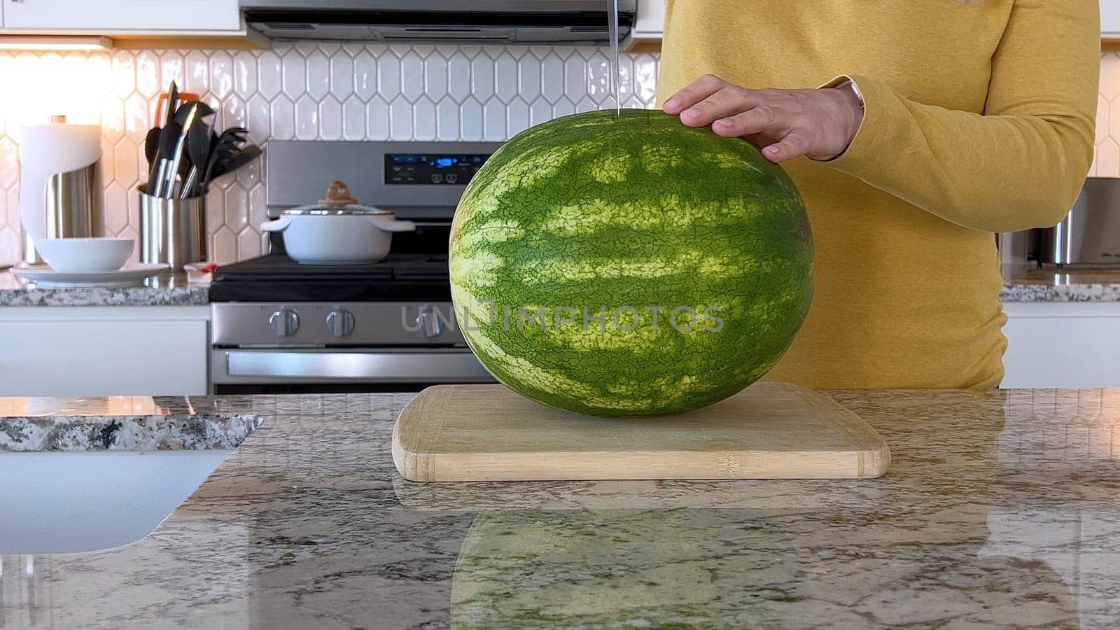 Woman Slicing Watermelon in a Modern Kitchen by arinahabich