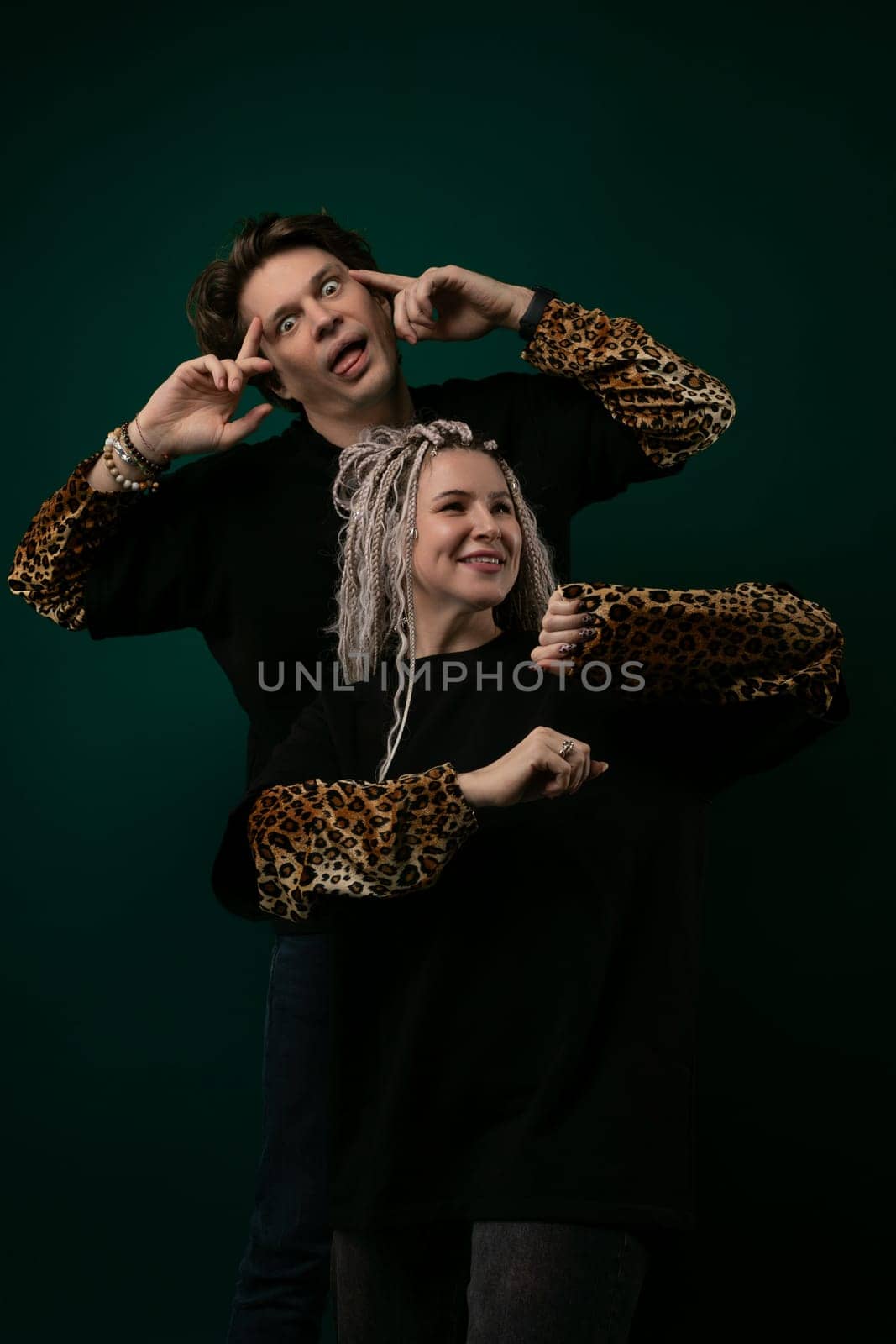 A man and a woman are standing together, smiling and posing for a picture. The man has his arm around the womans shoulder, while she leans into him. They both look happy and relaxed.