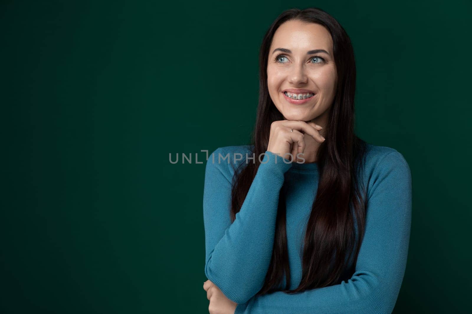 A woman wearing a blue shirt is striking a pose for a photograph. She is standing confidently, with her hands on her hips and a slight smile on her face.