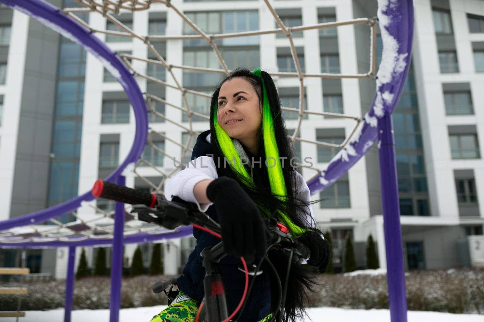 A woman with green hair is actively playing with a basketball hoop, shooting hoops and practicing her basketball skills. She appears focused and determined as she engages in the sporty activity.